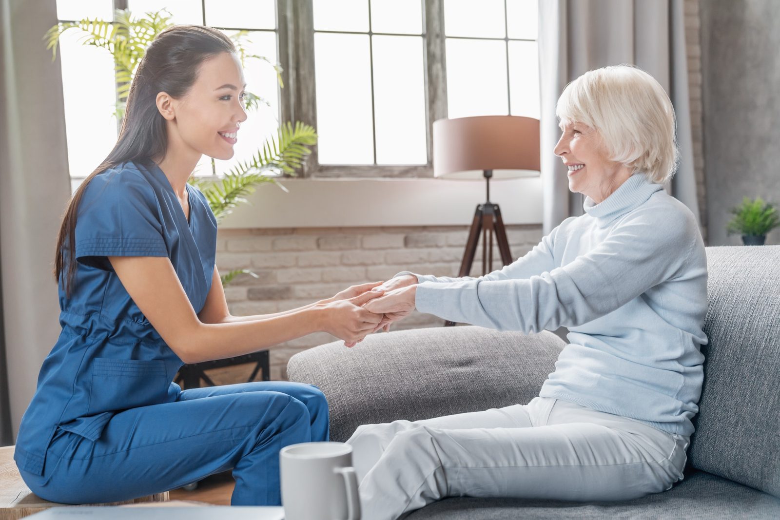 Caregiver holding hands with a member in a bright living room